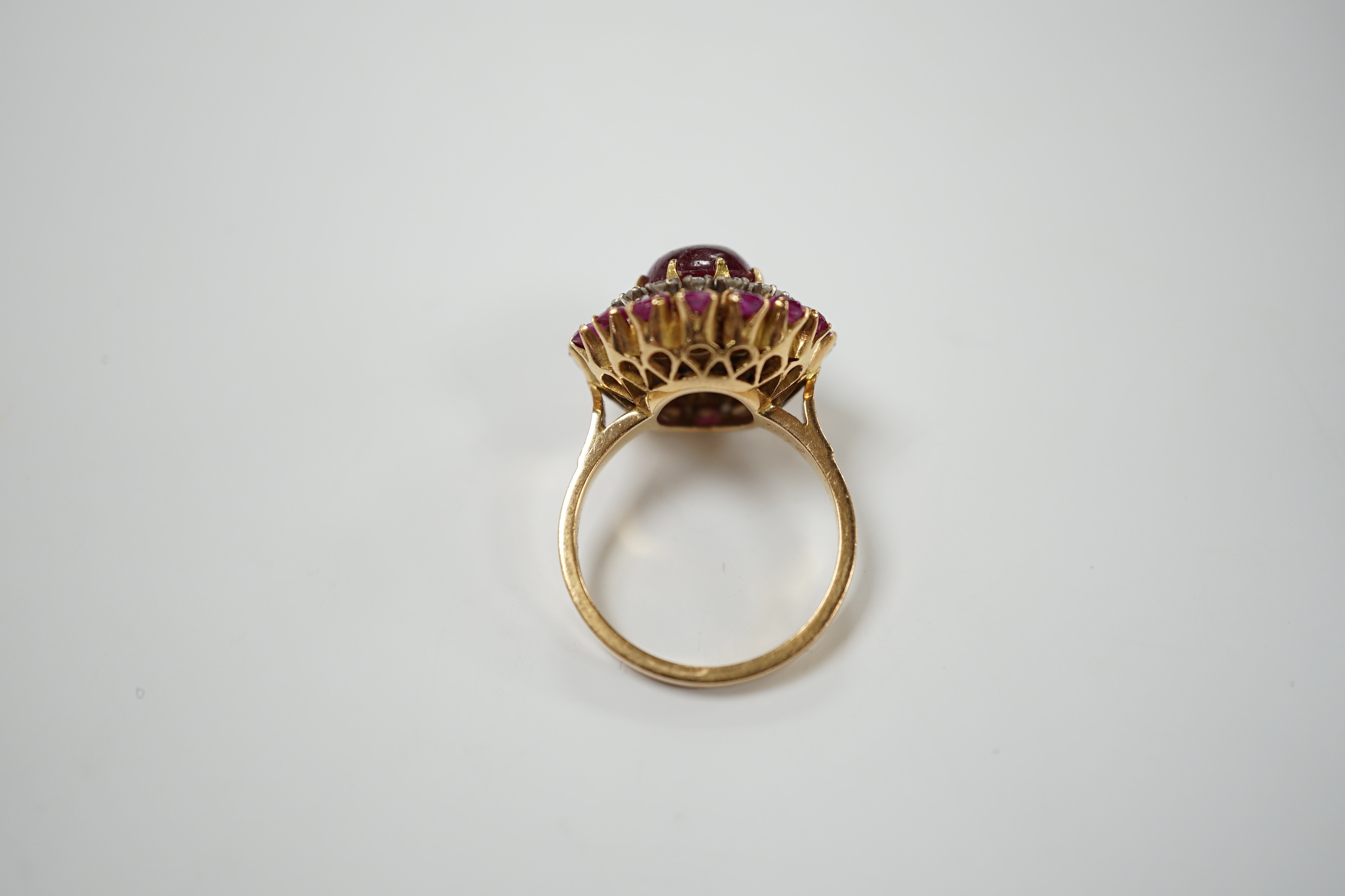 A yellow metal, ruby and diamond set circular cluster dress ring, with central cabochon ruby, size M/N, gross 8.2 grams.